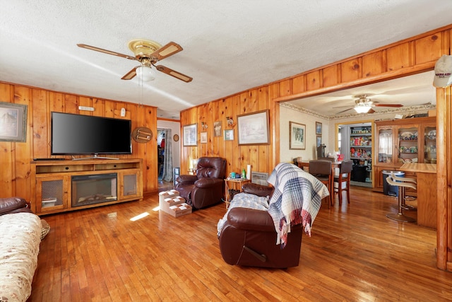 living room featuring a textured ceiling, a ceiling fan, and wood-type flooring