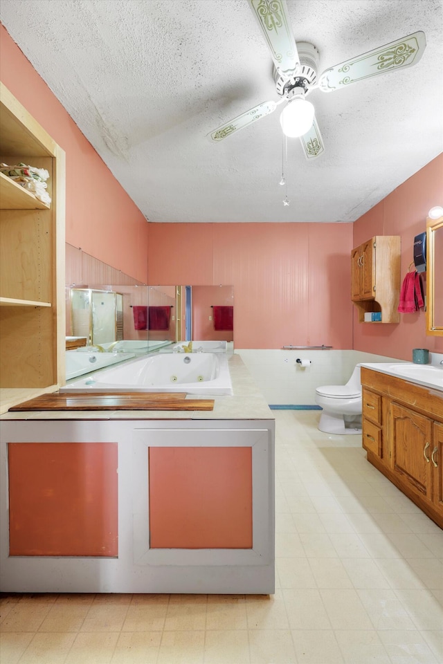 bathroom with vanity, toilet, a whirlpool tub, a textured ceiling, and a ceiling fan