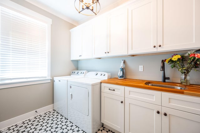 clothes washing area with independent washer and dryer, a sink, cabinet space, baseboards, and light floors