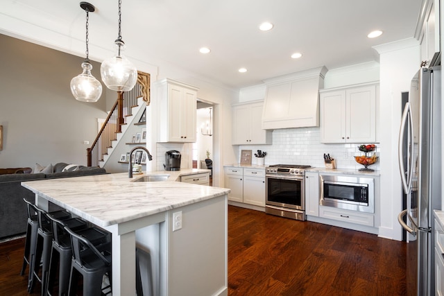 kitchen with a sink, dark wood-type flooring, custom range hood, appliances with stainless steel finishes, and white cabinetry