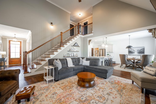 living area with crown molding, baseboards, stairs, a high ceiling, and wood finished floors