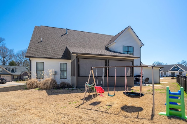 back of property featuring a playground and a shingled roof
