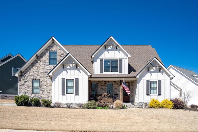 view of front facade featuring stone siding, board and batten siding, and roof with shingles