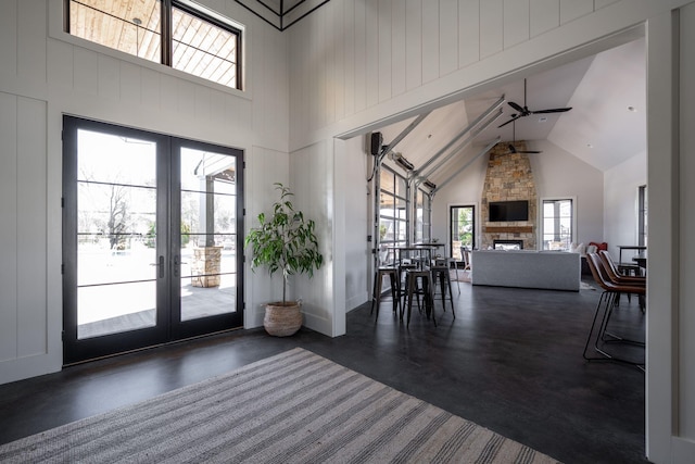 foyer featuring french doors, a fireplace, concrete flooring, and ceiling fan