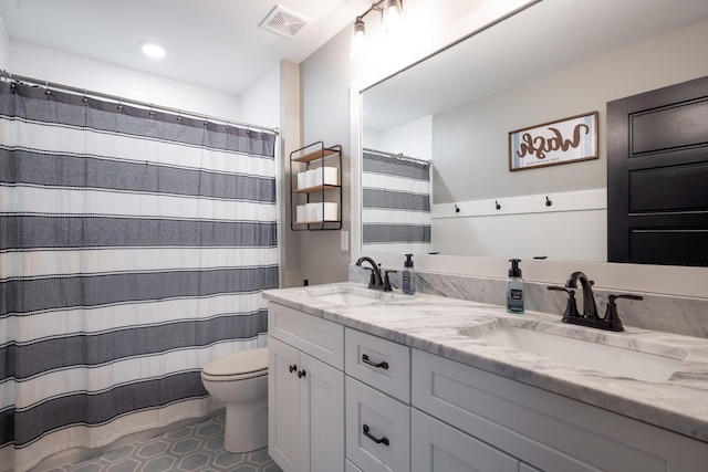 bathroom featuring double vanity, visible vents, toilet, and a sink