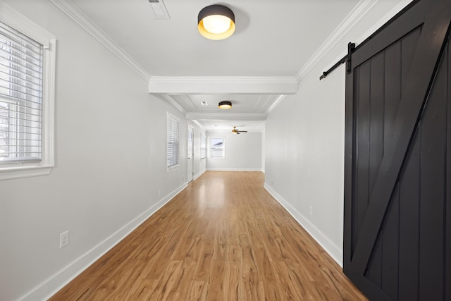 hall featuring a barn door, visible vents, a wealth of natural light, and ornamental molding