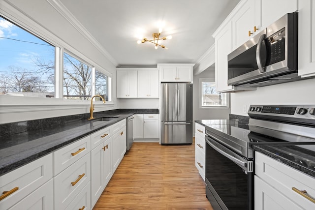 kitchen with ornamental molding, a sink, plenty of natural light, appliances with stainless steel finishes, and white cabinets