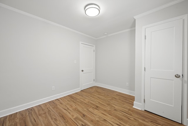 spare room with baseboards, wood finished floors, and ornamental molding