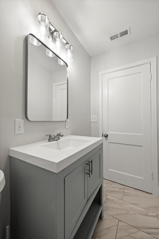 half bath with visible vents, marble finish floor, and vanity