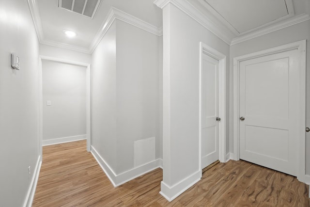 hallway with visible vents, baseboards, light wood-style flooring, and ornamental molding