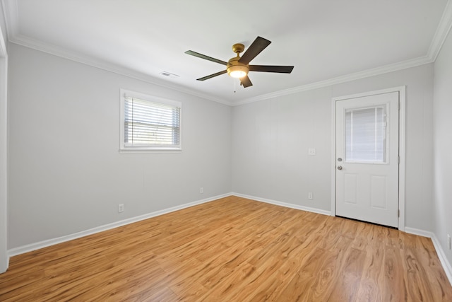 empty room with baseboards, visible vents, light wood finished floors, ceiling fan, and crown molding