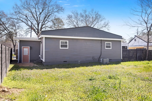 rear view of property featuring crawl space, central AC, a yard, and fence