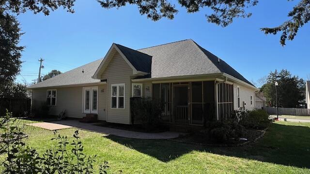 back of property with entry steps, a sunroom, a patio area, and a lawn