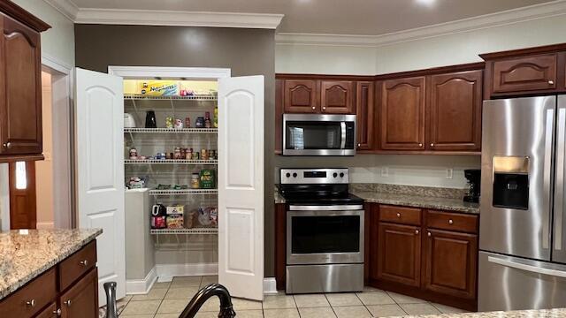 kitchen with crown molding, stainless steel appliances, light stone counters, and light tile patterned floors