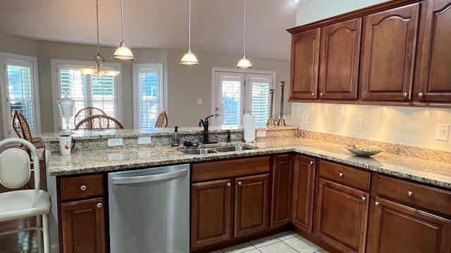 kitchen with a sink, a peninsula, light stone counters, and dishwasher