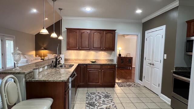 kitchen with light tile patterned floors, light stone counters, a sink, a peninsula, and stainless steel appliances