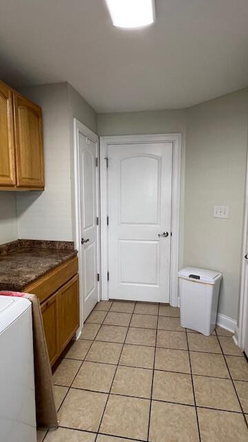 kitchen featuring dark countertops, light tile patterned floors, stove, and brown cabinets