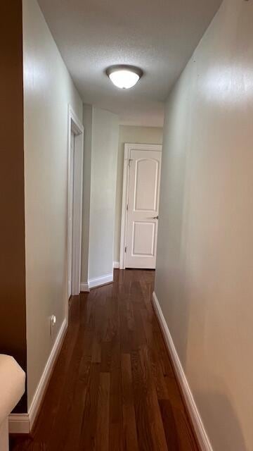 corridor featuring baseboards and wood finished floors