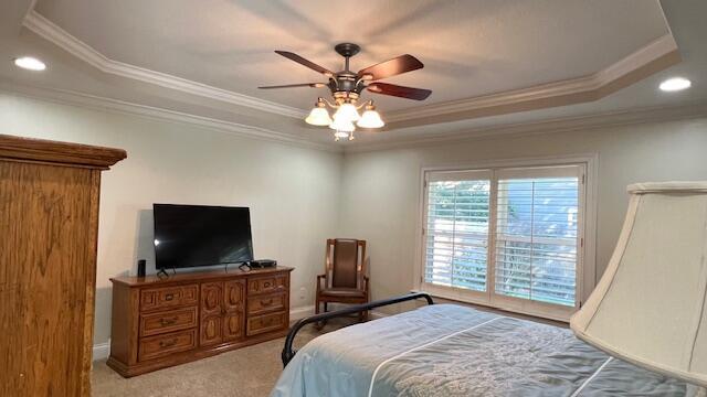 carpeted bedroom with crown molding, a raised ceiling, ceiling fan, and recessed lighting