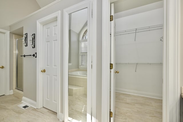 bathroom featuring a bath, a stall shower, baseboards, and a spacious closet