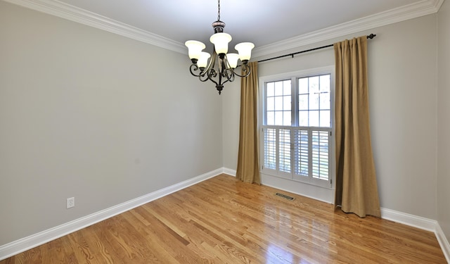spare room with an inviting chandelier, light wood-style floors, baseboards, and ornamental molding