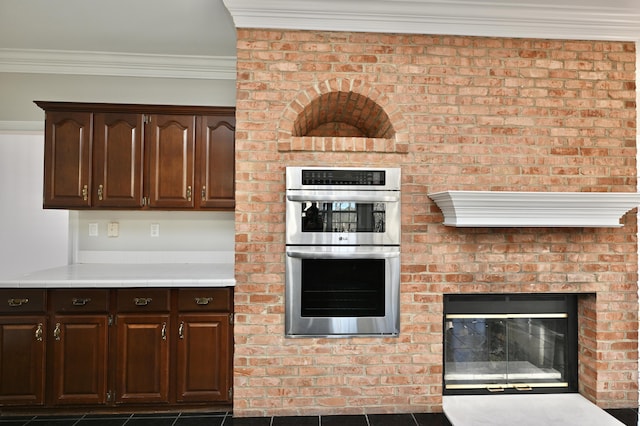 kitchen featuring ornamental molding, tile patterned flooring, light countertops, dark brown cabinets, and stainless steel double oven