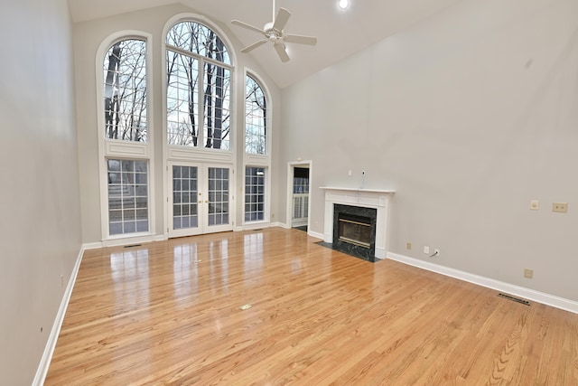 unfurnished living room with wood finished floors, high vaulted ceiling, ceiling fan, and visible vents