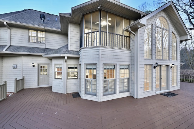 back of property featuring a shingled roof and a deck