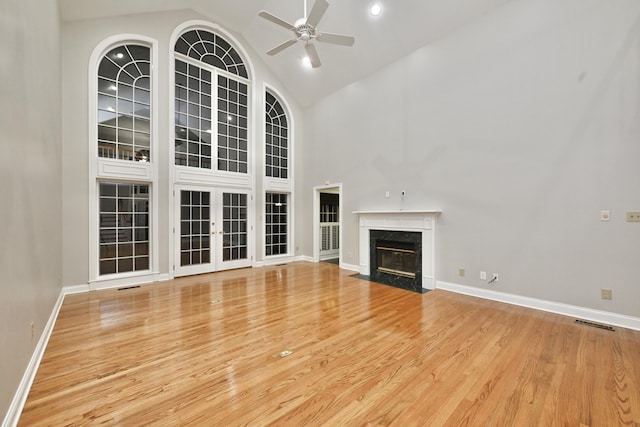 unfurnished living room with a high end fireplace, baseboards, wood finished floors, and ceiling fan
