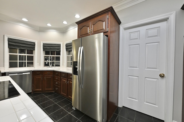 kitchen featuring crown molding, appliances with stainless steel finishes, tile counters, and dark tile patterned floors
