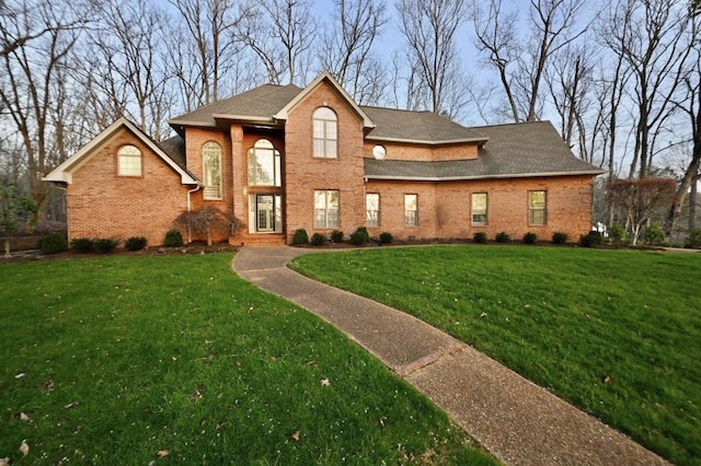 traditional-style home with a front yard, brick siding, and a shingled roof