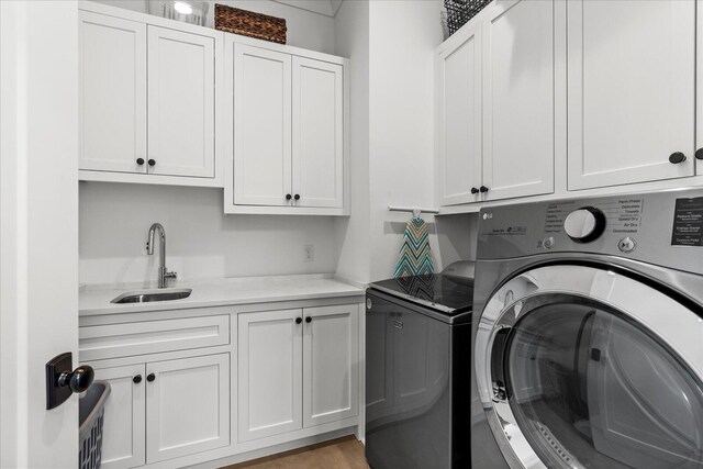 washroom featuring washing machine and dryer, a sink, and cabinet space