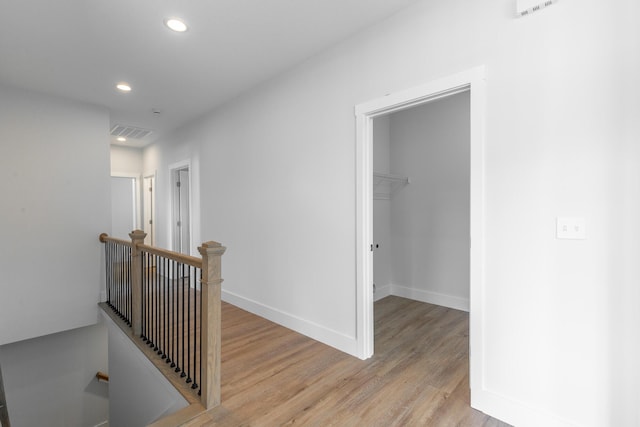 hall featuring visible vents, baseboards, recessed lighting, an upstairs landing, and light wood-type flooring