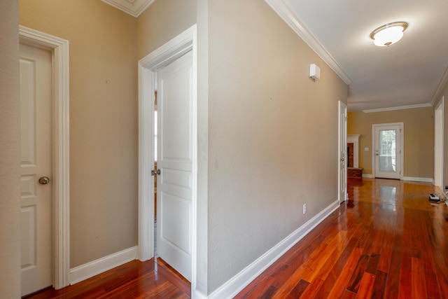 corridor with wood finished floors, baseboards, and ornamental molding