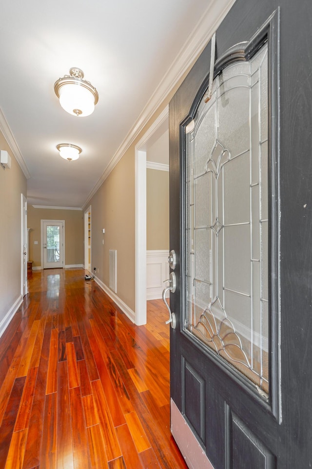 foyer entrance featuring hardwood / wood-style floors, crown molding, baseboards, and visible vents