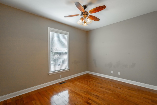 spare room with a ceiling fan, hardwood / wood-style flooring, baseboards, and visible vents