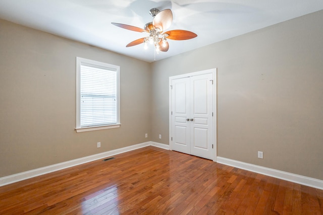 empty room featuring hardwood / wood-style floors, visible vents, baseboards, and ceiling fan