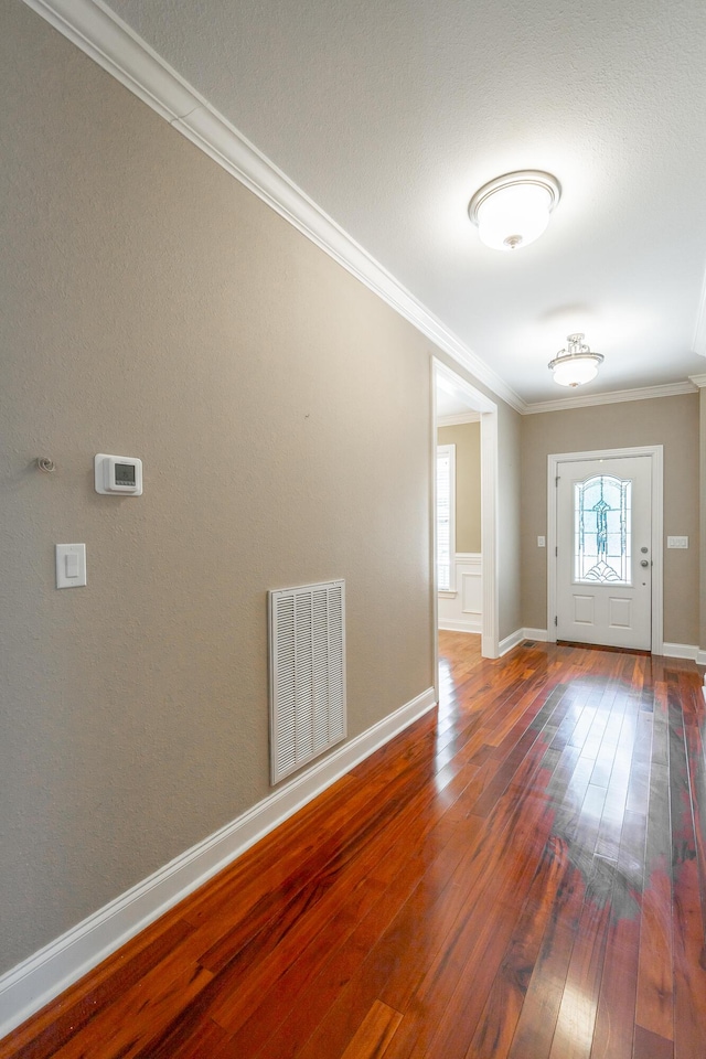 foyer with visible vents, baseboards, crown molding, and hardwood / wood-style flooring