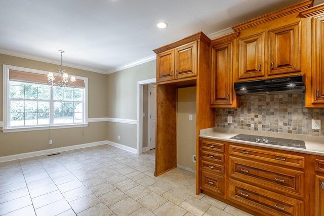 kitchen featuring brown cabinets, under cabinet range hood, black electric cooktop, tasteful backsplash, and a chandelier