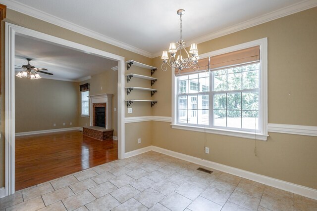 unfurnished dining area featuring visible vents, a fireplace with raised hearth, ceiling fan with notable chandelier, crown molding, and baseboards