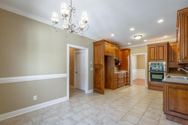 kitchen with an inviting chandelier, double oven, crown molding, and a sink