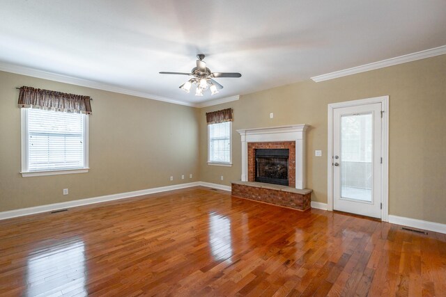 unfurnished living room featuring visible vents, ornamental molding, hardwood / wood-style flooring, a brick fireplace, and ceiling fan