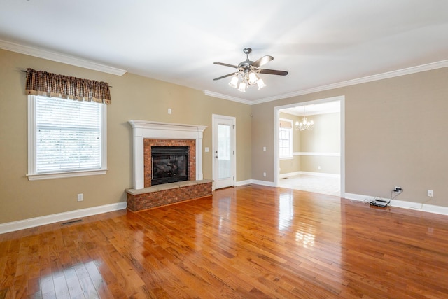 unfurnished living room with crown molding, baseboards, hardwood / wood-style floors, ceiling fan with notable chandelier, and a fireplace