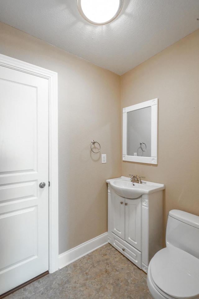 bathroom with baseboards, toilet, and vanity