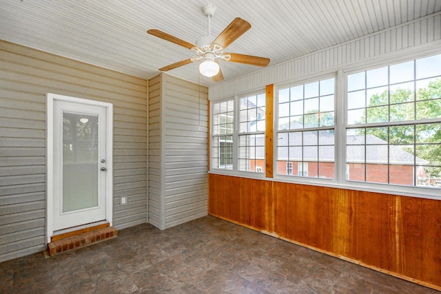 unfurnished sunroom featuring wooden walls and stone finish floor