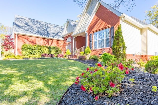 view of side of property with brick siding and a lawn