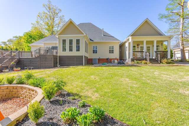 back of property with roof with shingles, stairs, a yard, and a porch