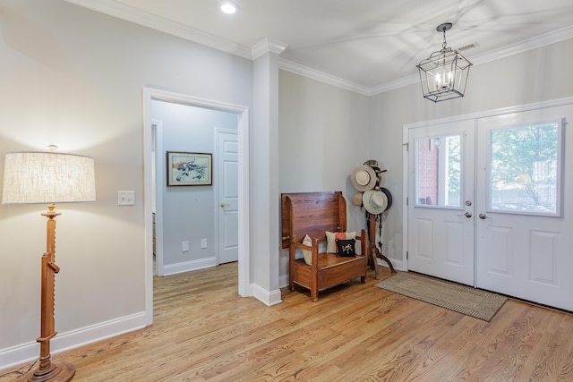 foyer entrance with french doors, baseboards, light wood finished floors, a chandelier, and ornamental molding