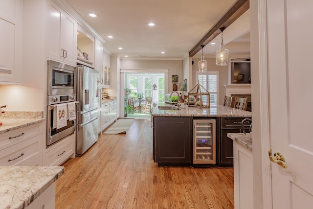 kitchen with crown molding, appliances with stainless steel finishes, a sink, beverage cooler, and white cabinetry