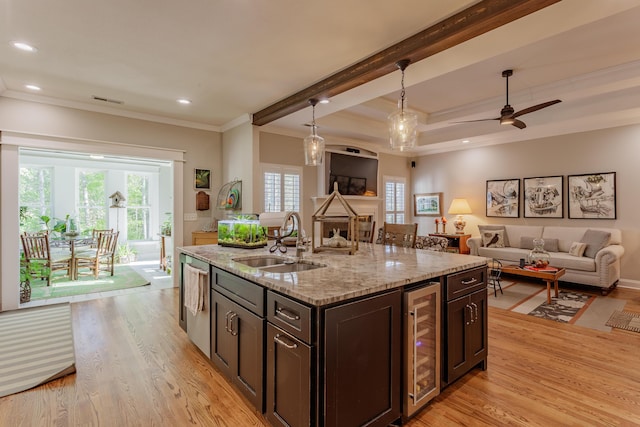 kitchen with crown molding, beverage cooler, light wood-type flooring, a sink, and hanging light fixtures